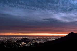 A panoramic city skyline at dusk with twinkling lights and a soft purple sky