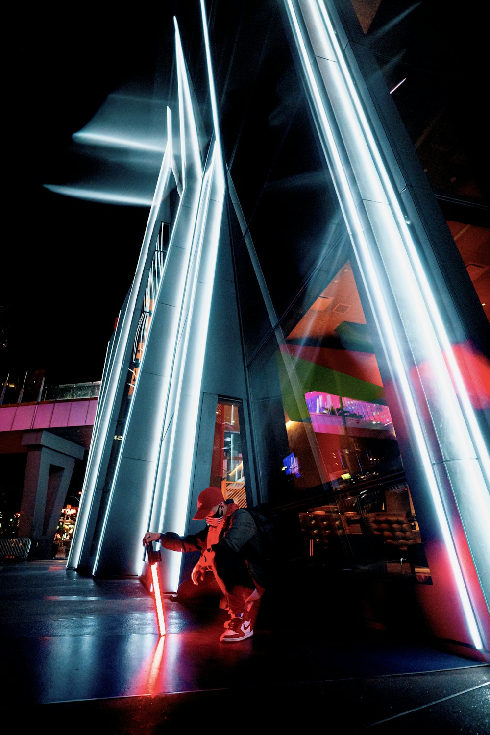 man in red jacket sitting on bench near building during night time