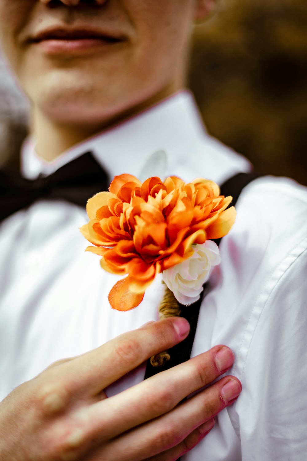 homme en chemise blanche tenant une fleur d’oranger