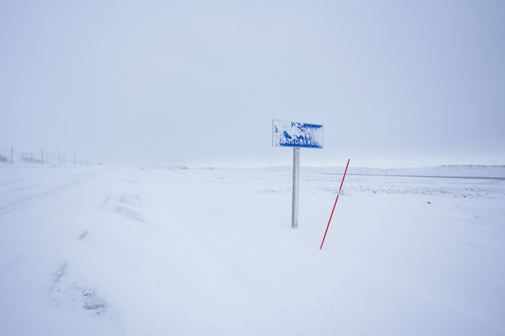 blue and white road sign on snow covered ground