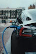 A sleek electric car parked quietly on a city street with a driver waiting inside, city skyline in the background.