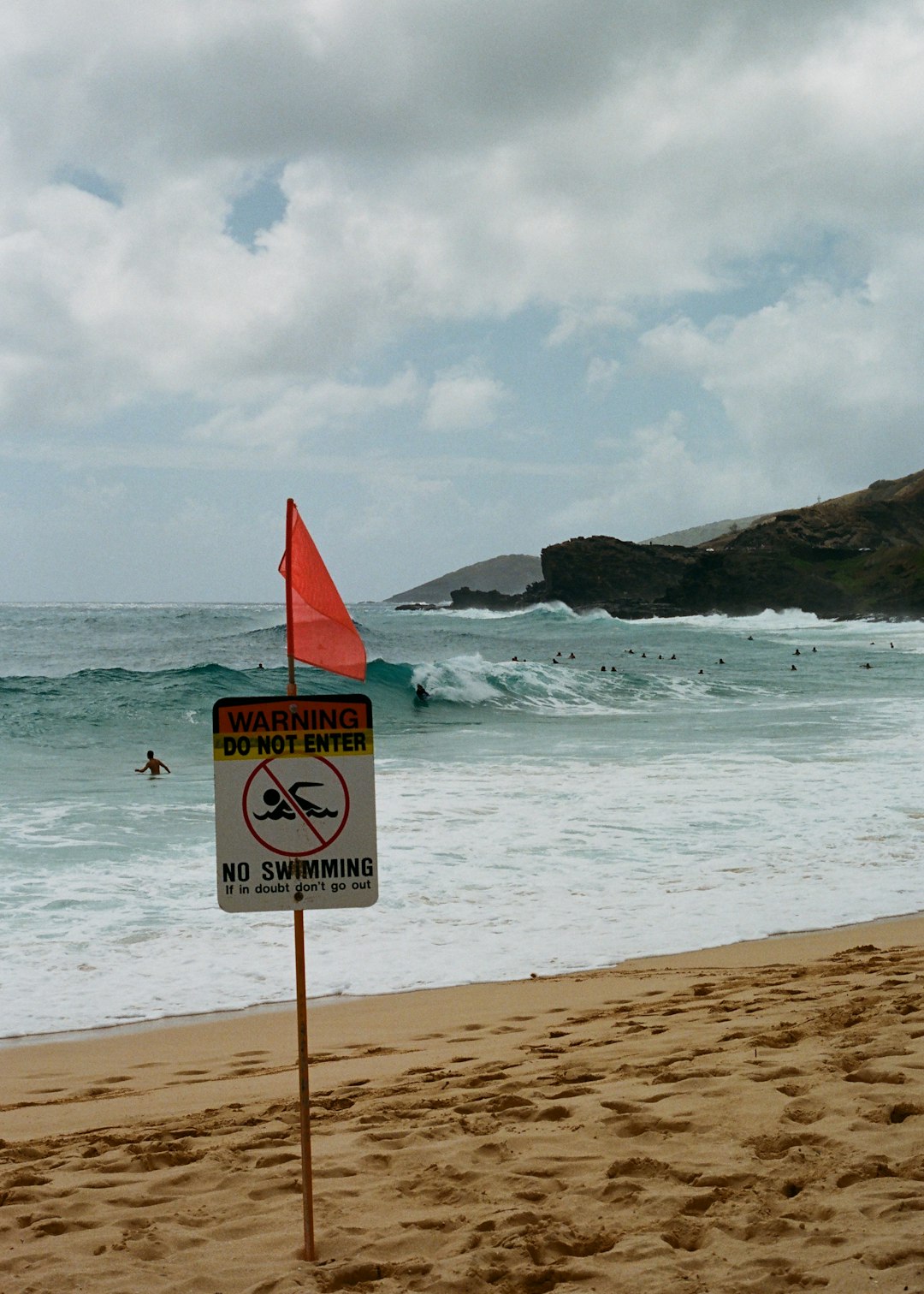 red and white beach signage on beach during daytime