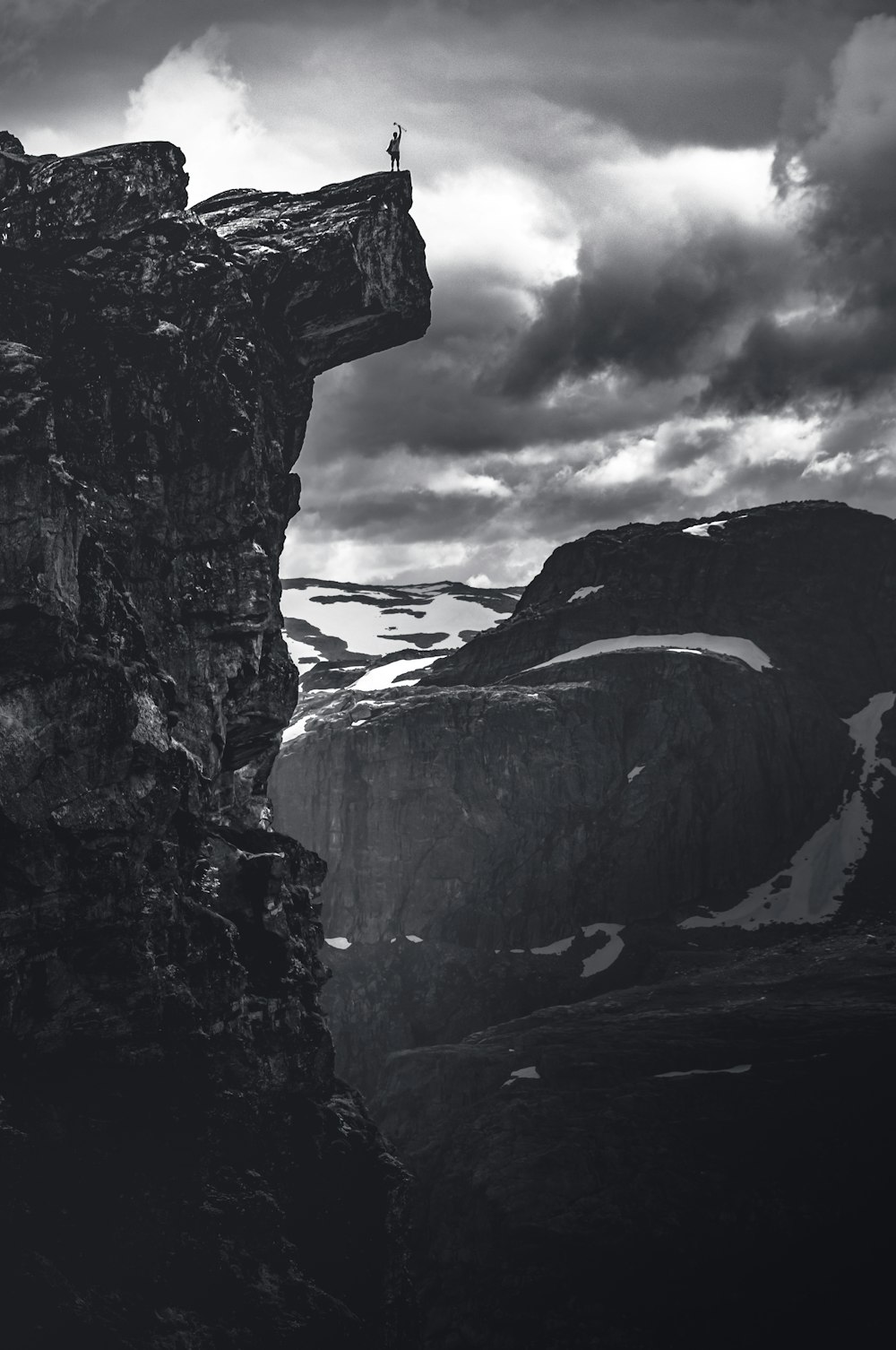 grayscale photo of rocky mountain under cloudy sky