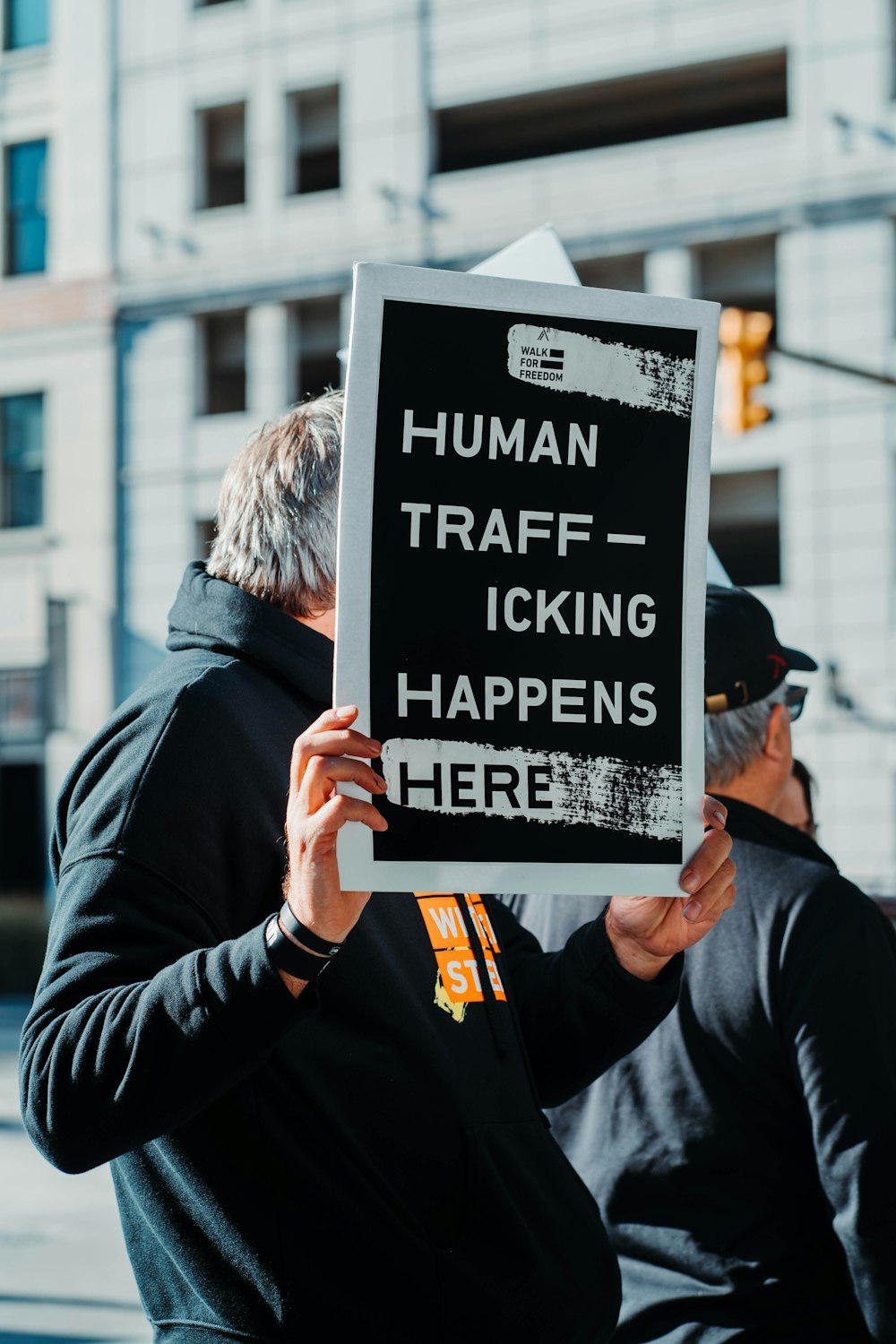 man in black jacket holding black and white quote board