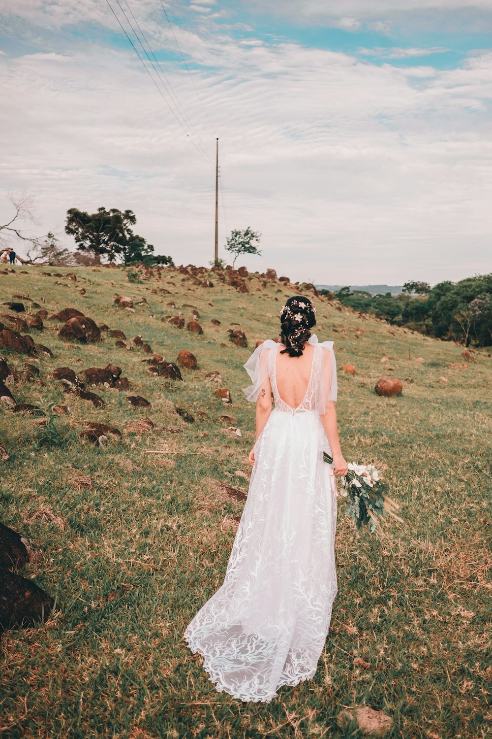 woman in white wedding gown standing on green grass field during daytime