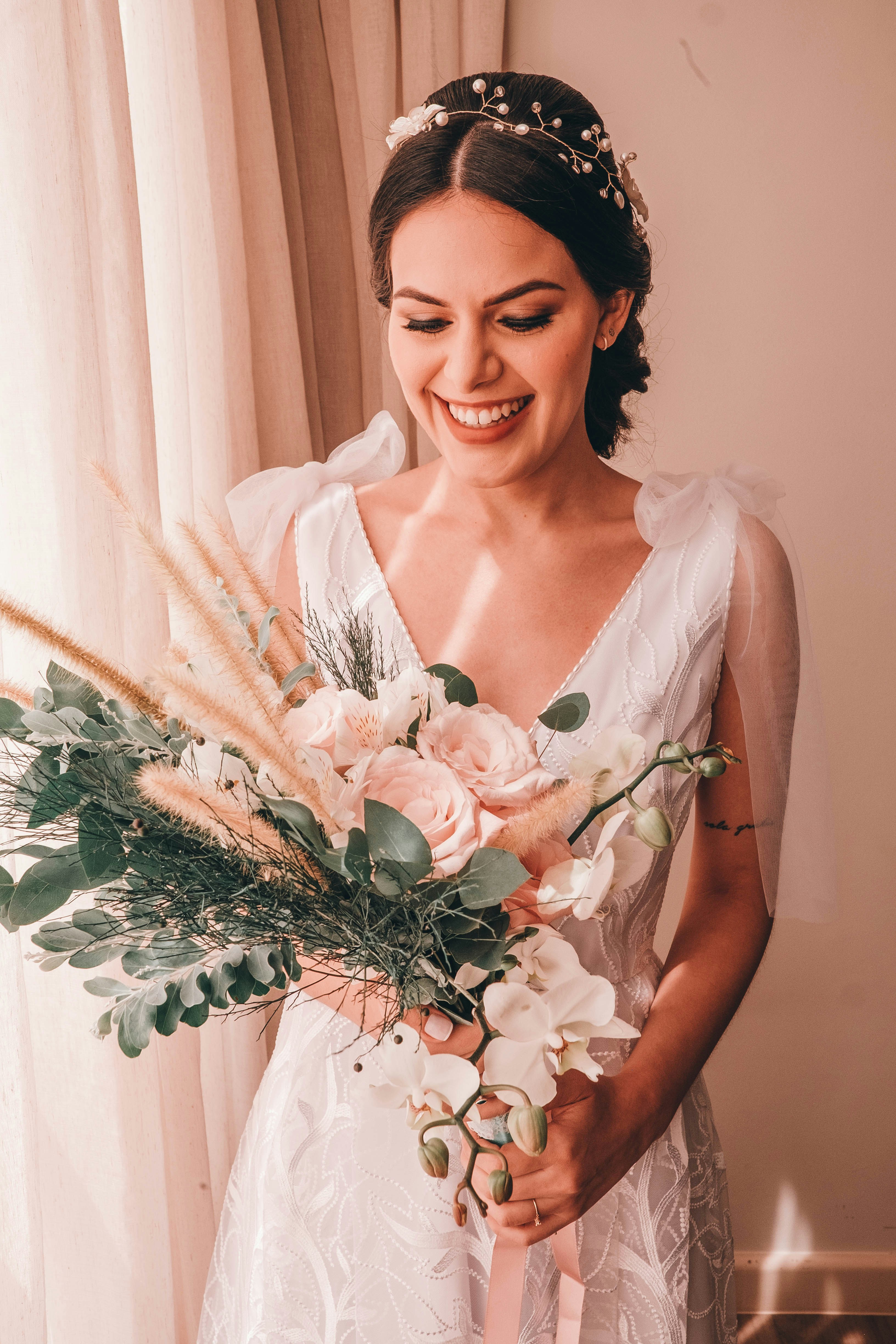 woman in white sleeveless dress holding white flower bouquet