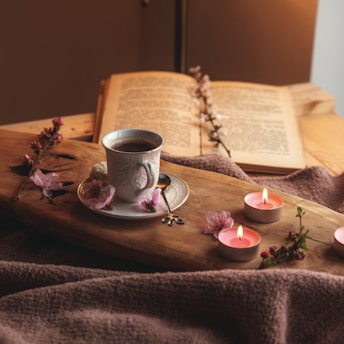 A serene morning scene with a cup of herbal tea, a notebook, and a soft navy blue blanket.