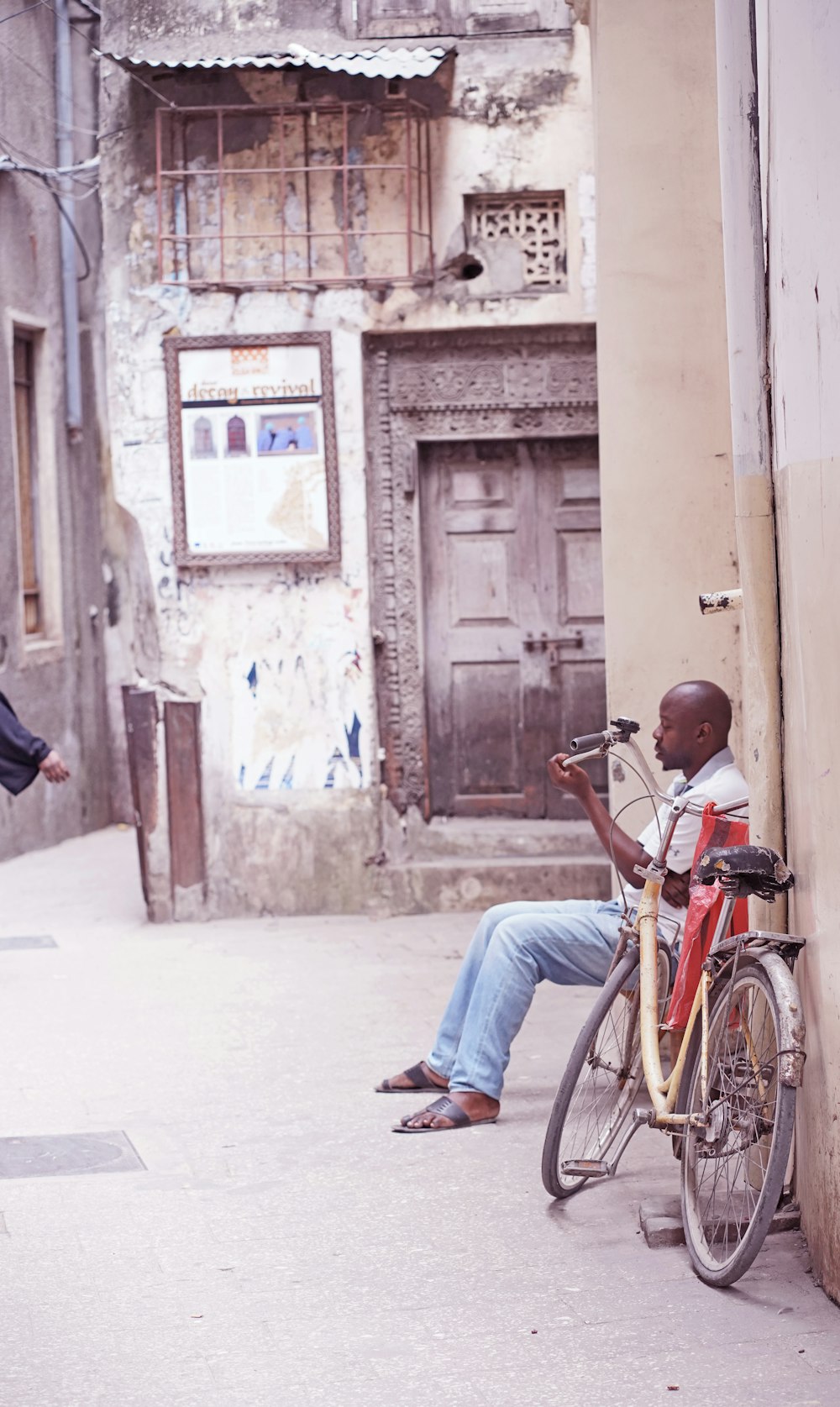 man in blue denim jeans sitting on red city bicycle during daytime