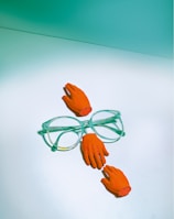 green framed eyeglasses beside orange rose