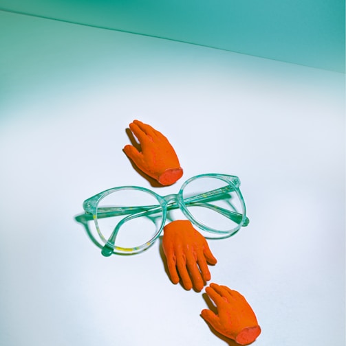 green framed eyeglasses beside orange rose