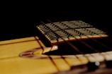 An artistic shot of a guitar with sheet music in the background.