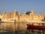 red and white boat on body of water near beige concrete building during daytime