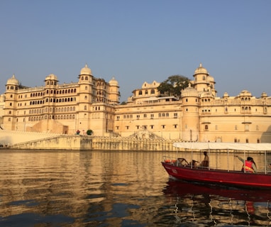 red and white boat on body of water near beige concrete building during daytime