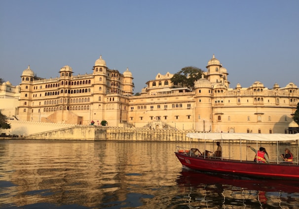 red and white boat on body of water near beige concrete building during daytime