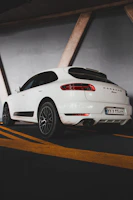 A Porsche Macan parked on a desert road flanked by rugged red rocks and cacti.
