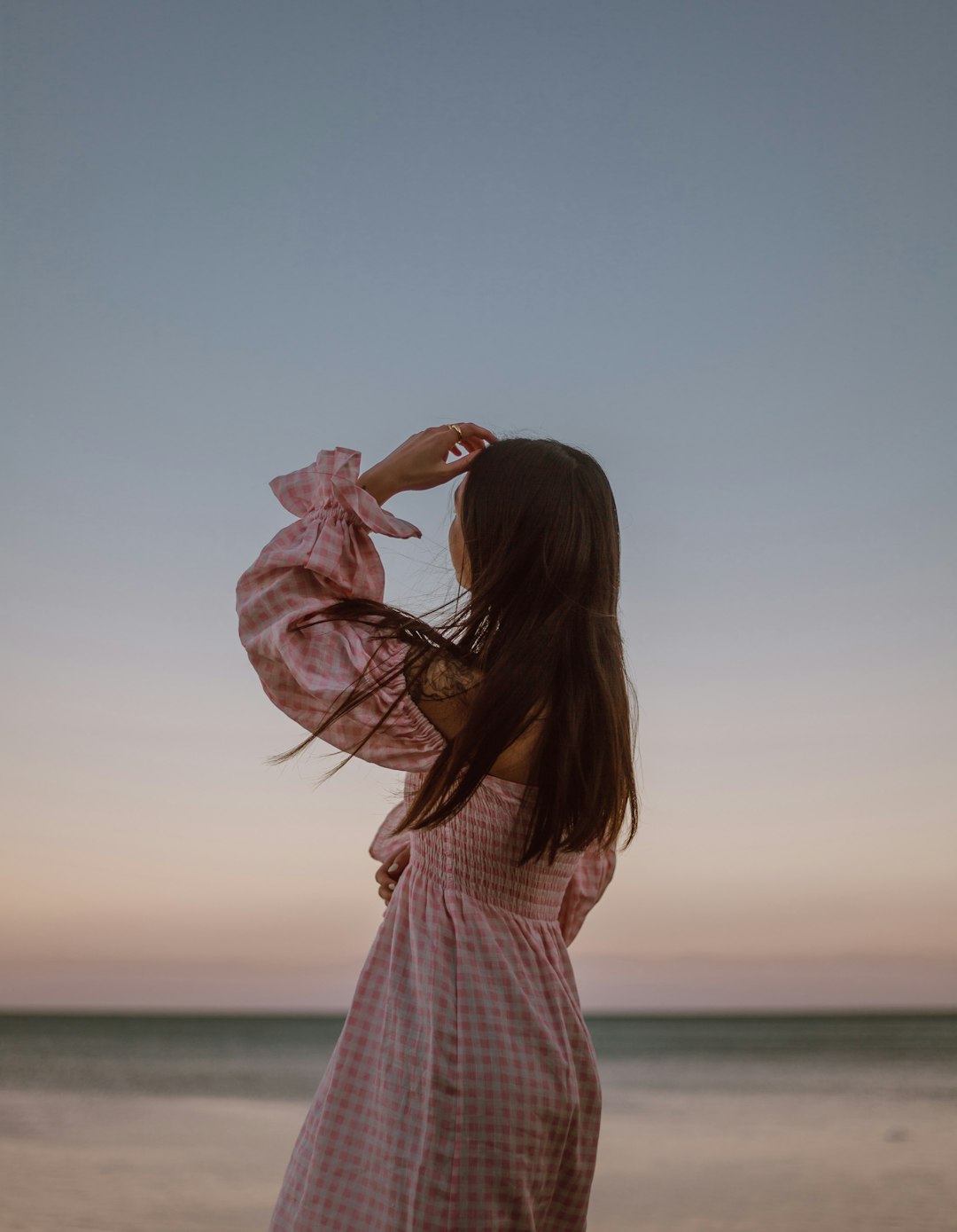 woman in white and red checkered dress standing near body of water during daytime