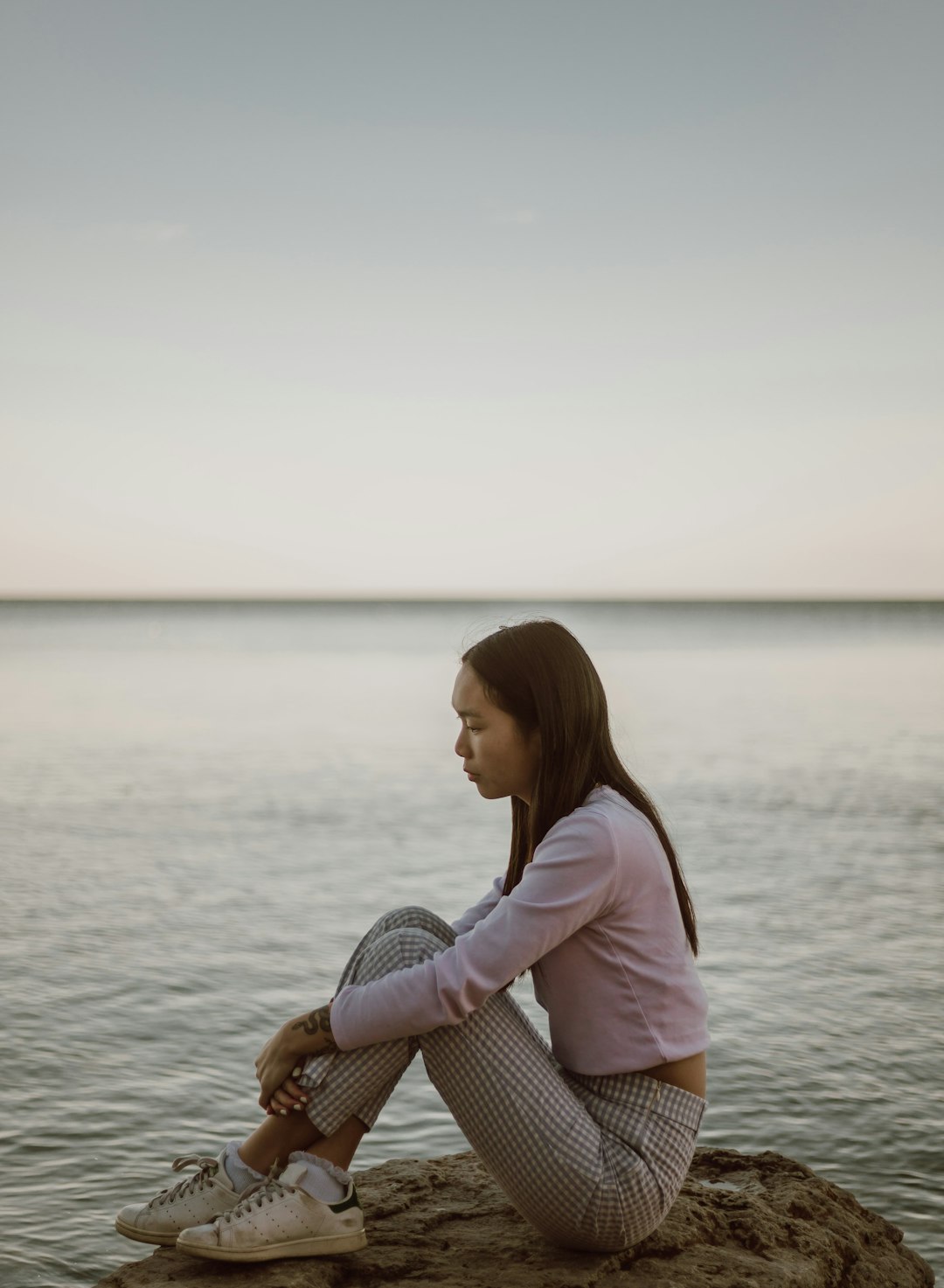 woman in pink shirt sitting on brown wooden dock during daytime