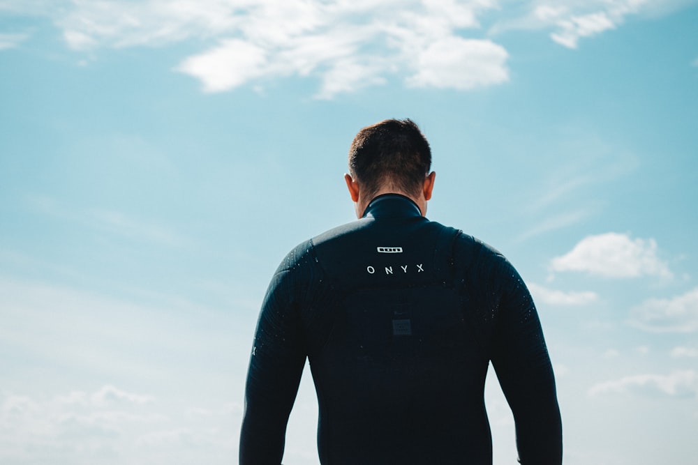 man in black long sleeve shirt standing under white clouds during daytime