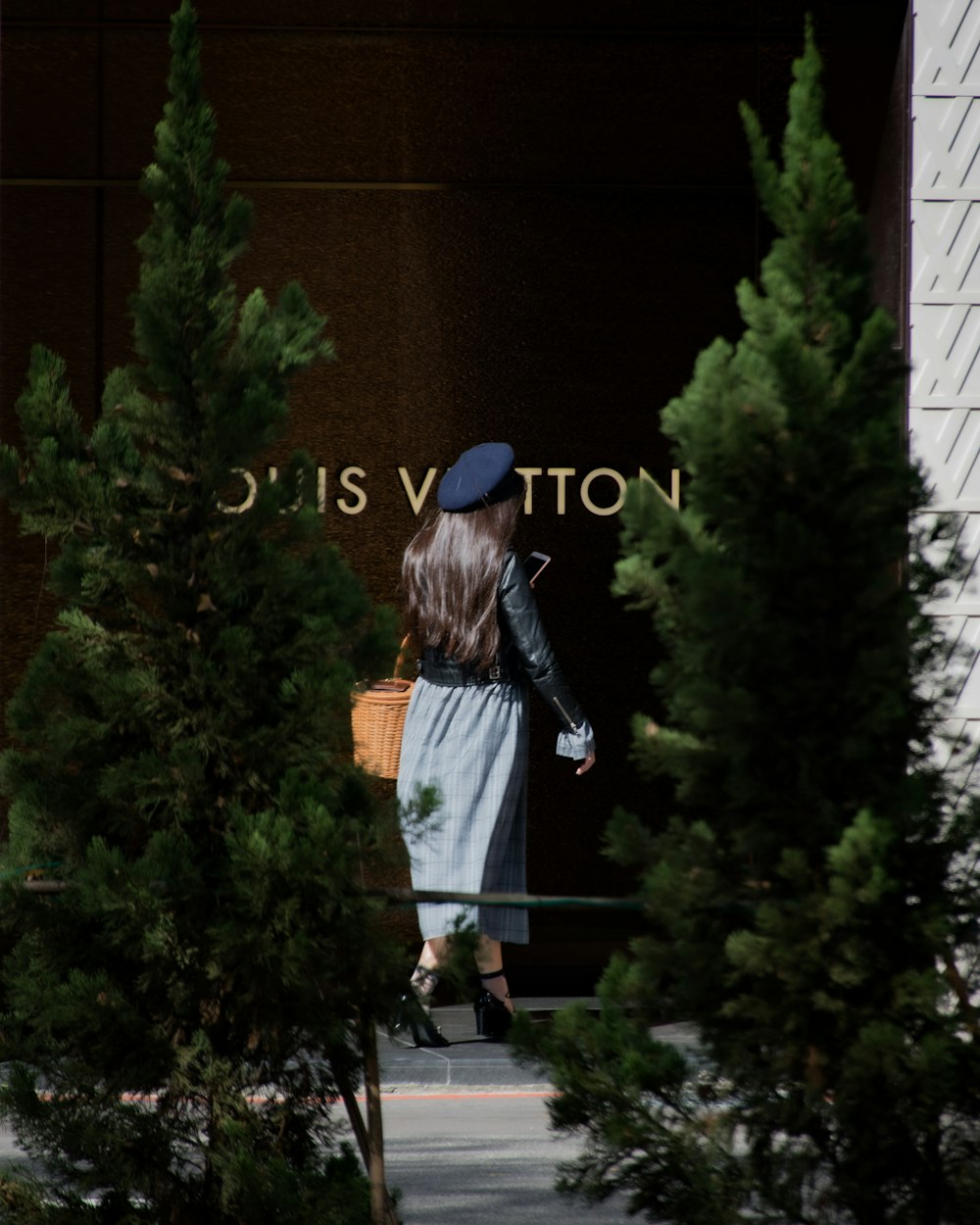 woman in black jacket and white skirt standing near green plant during daytime