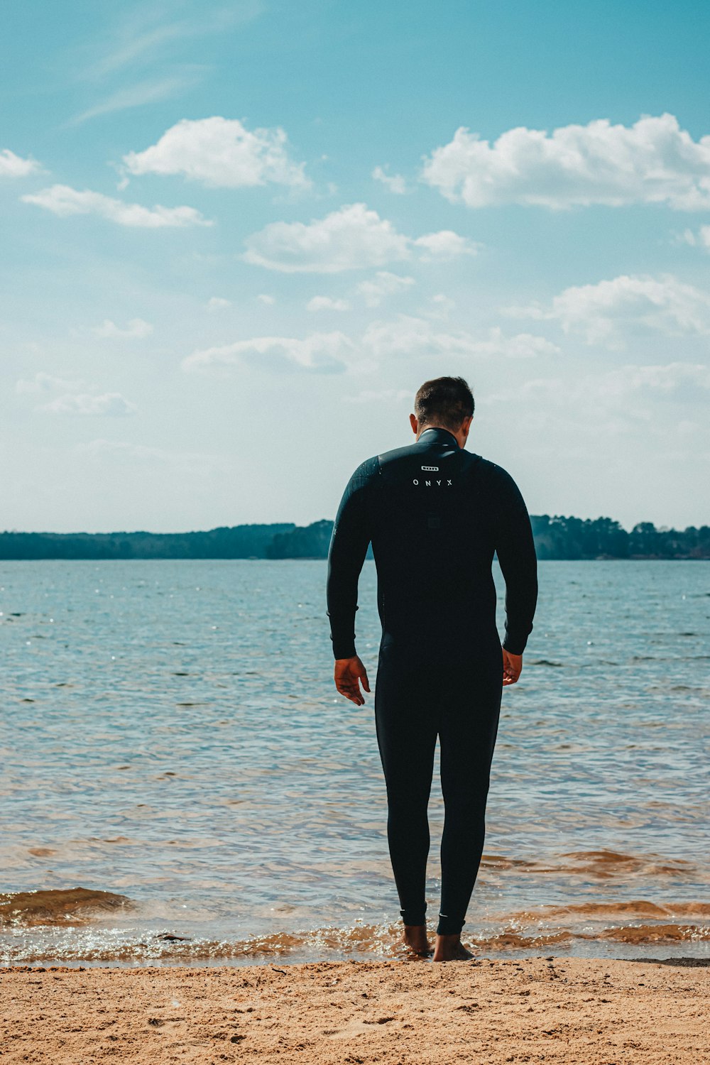 man in black jacket standing on sea shore during daytime