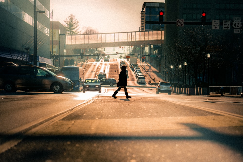 Frau in schwarzer Jacke und schwarzer Hose, die tagsüber auf dem Bürgersteig spazieren geht