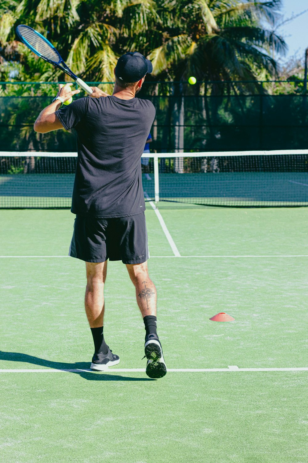 テニスをする黒いTシャツとショートパンツの男