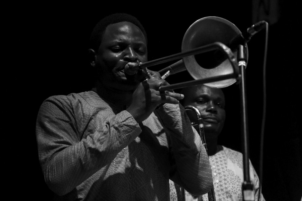 man in dress shirt playing trumpet