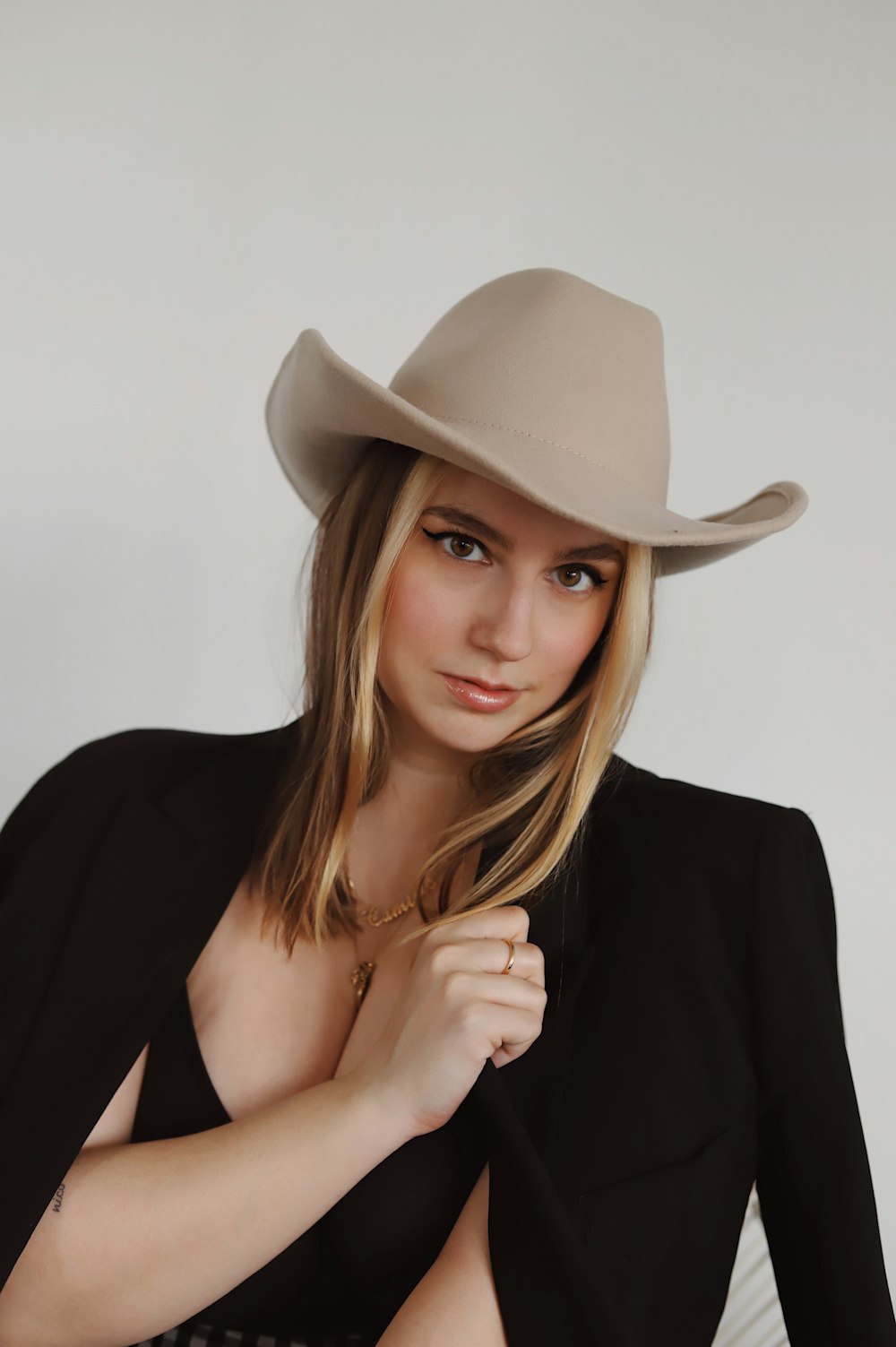 Femme en blazer noir et chapeau de cowboy blanc