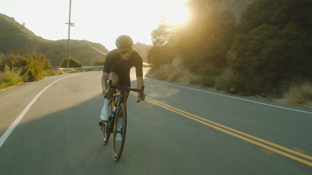 homme en t-shirt noir faisant du vélo sur la route pendant la journée