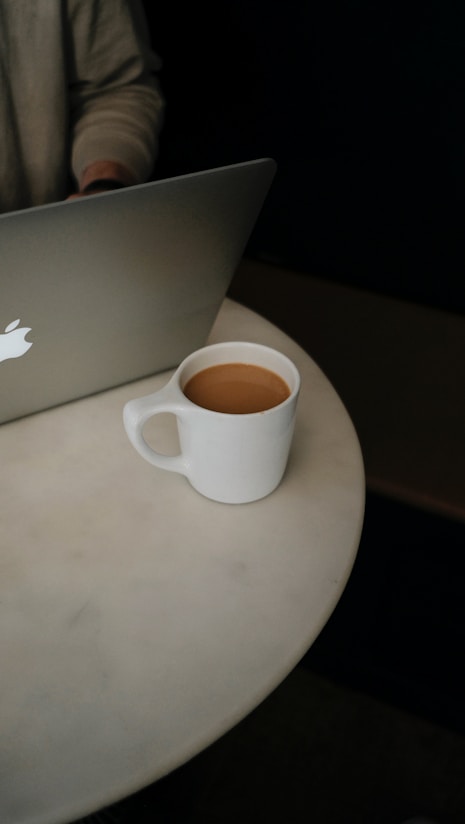 white ceramic mug on silver macbook
