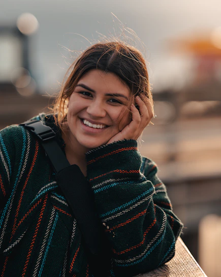 A warm, candid photo of 21nikoleta smiling in a creative studio filled with colorful design materials and playful icons.