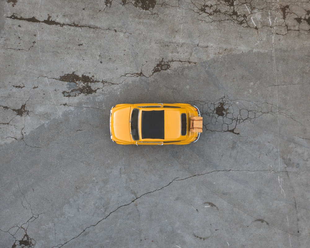 Gelbes Autospielzeug auf grauem Betonboden