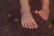 A pair of bare feet with clean toenails against a blurred earthy background.