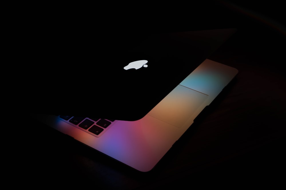 MacBook plateado sobre mesa negra