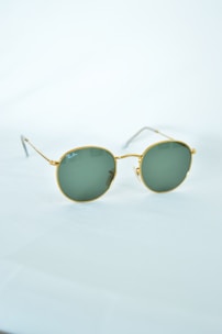 A close-up of gold sunglasses on a reflective surface.