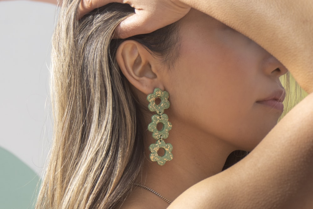 woman wearing silver and green flower earring