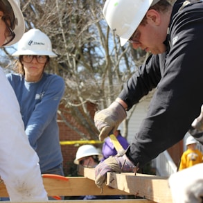 man in black jacket and white hard hat holding green plastic bottle