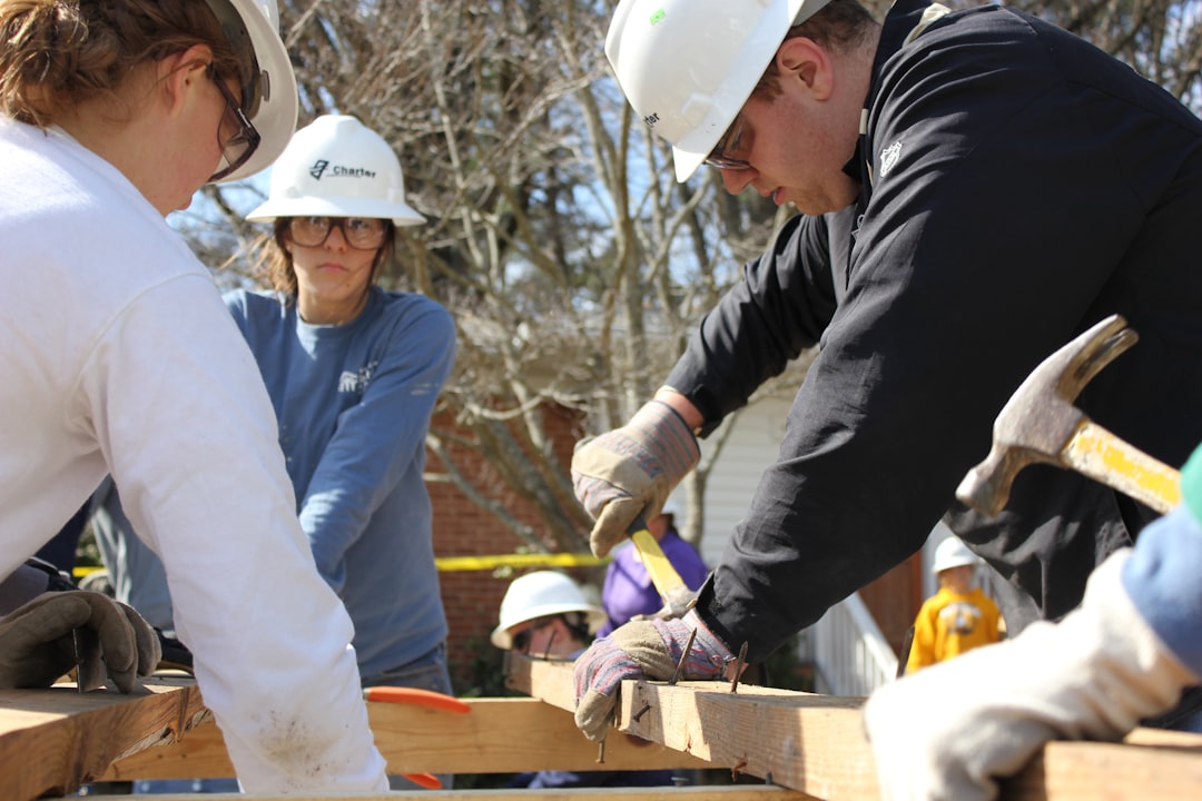 man in black jacket and white hard hat holding green plastic bottle, Habitat for Humanity project with undergraduate stu