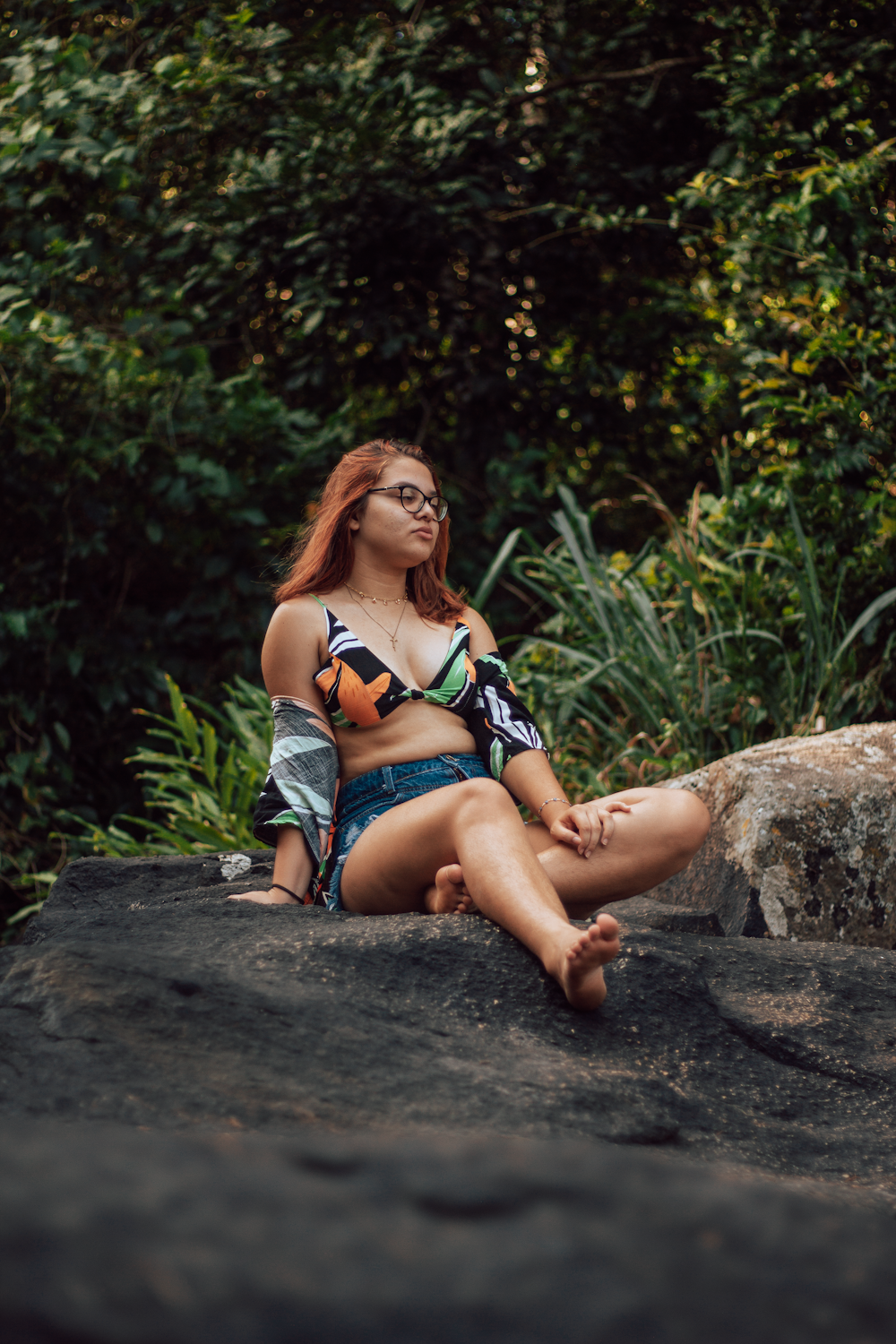 femme en bikini bleu et blanc assis sur la roche brune pendant la journée