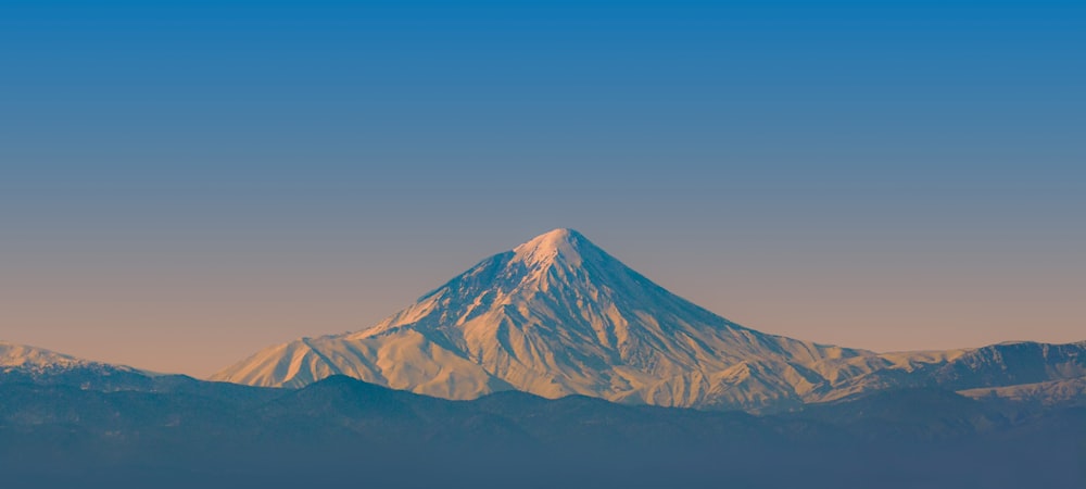 montanha marrom e branca sob o céu azul durante o dia