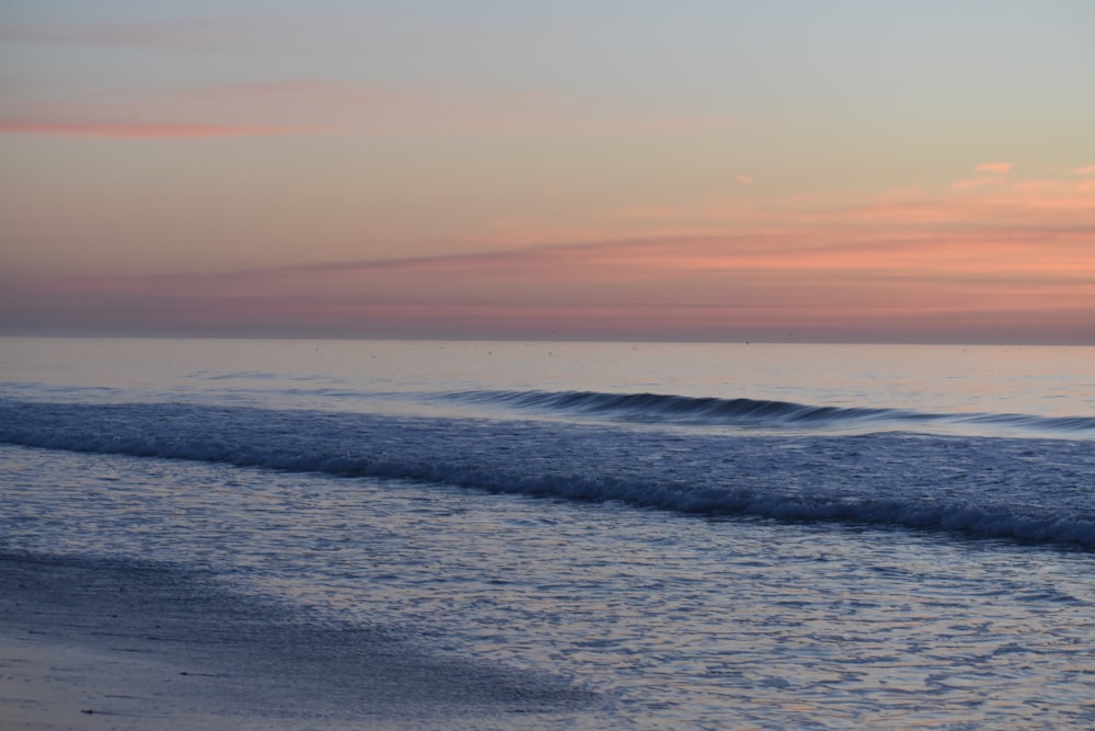 ocean waves crashing on shore during sunset