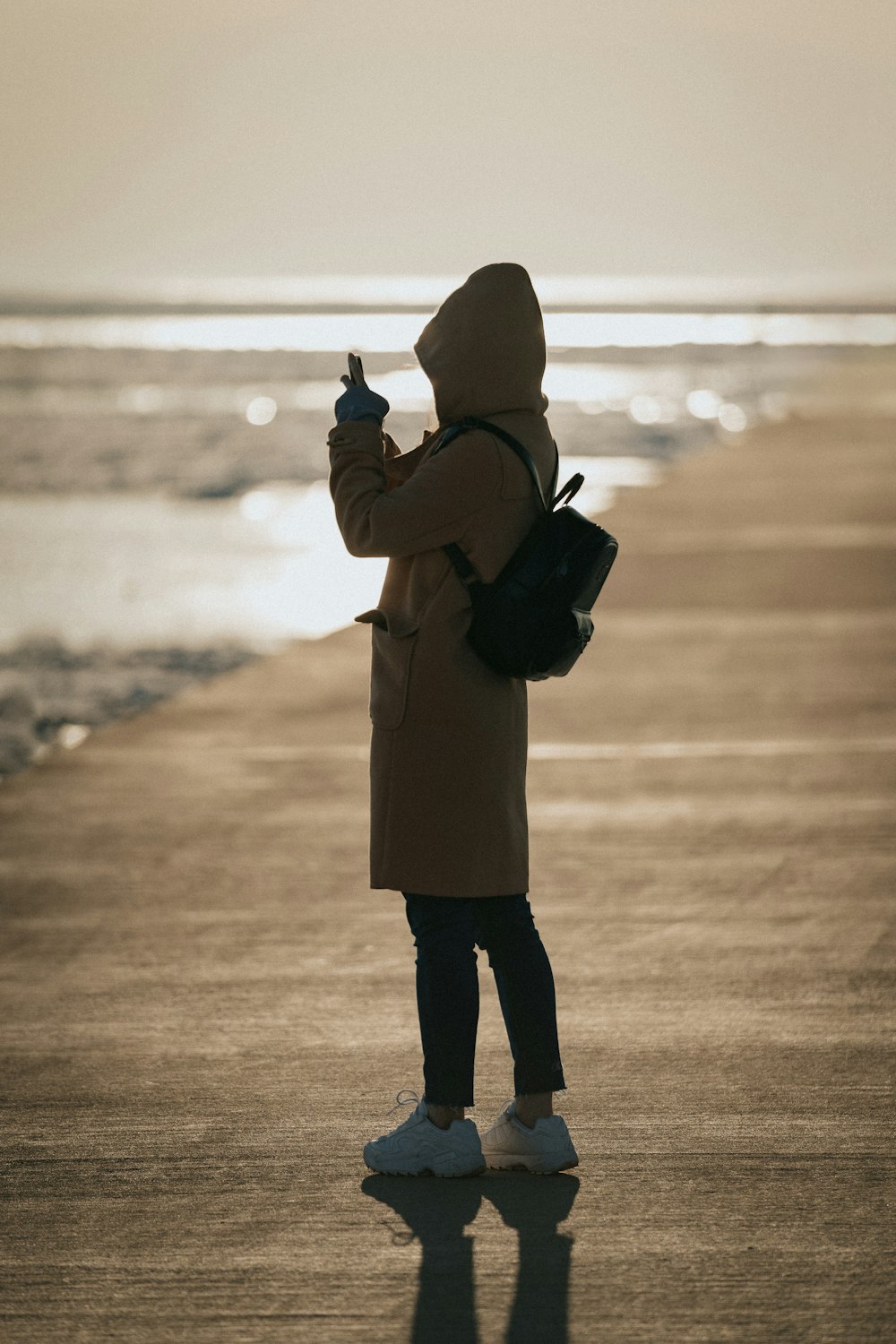 person in brown coat holding black dslr camera