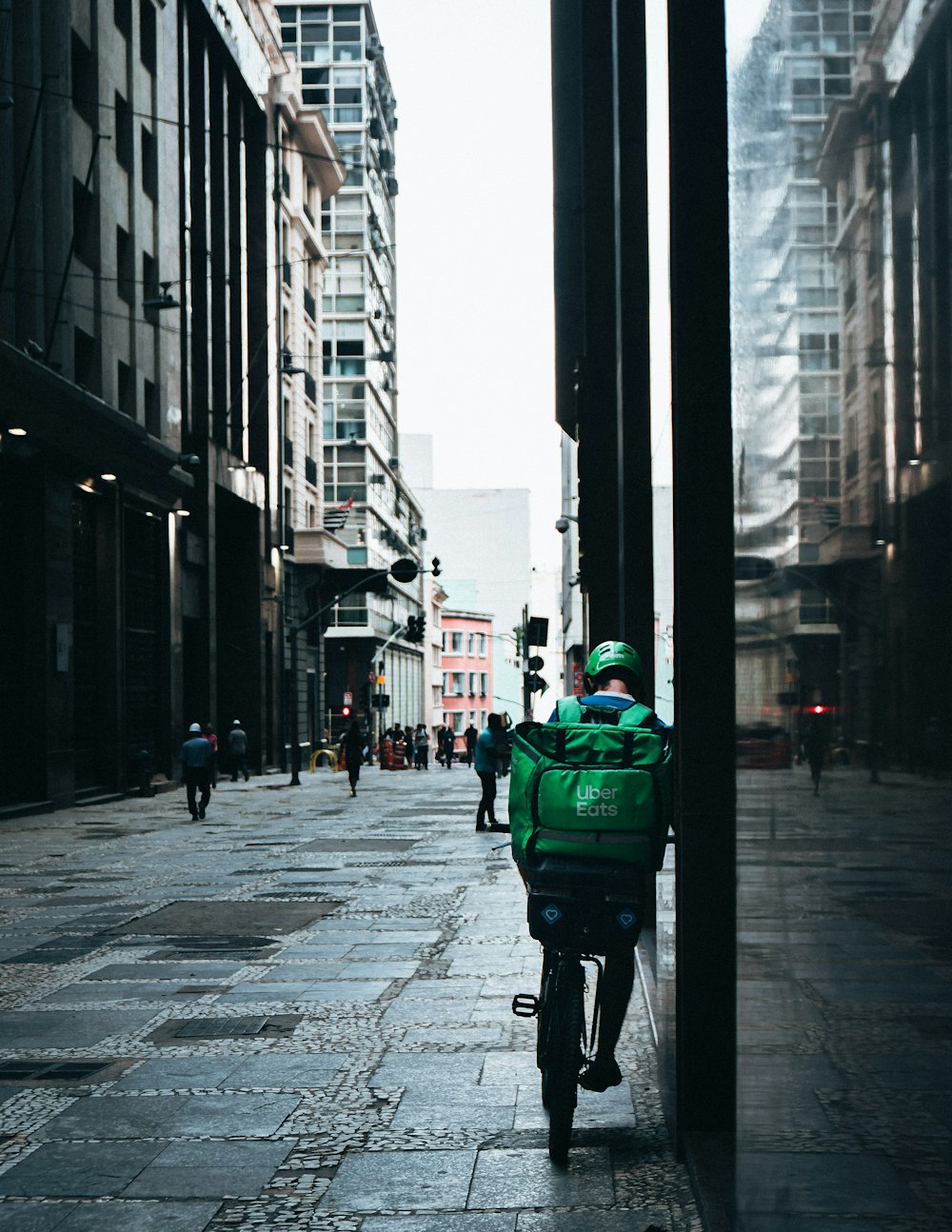 person in green jacket and black pants walking on sidewalk during daytime