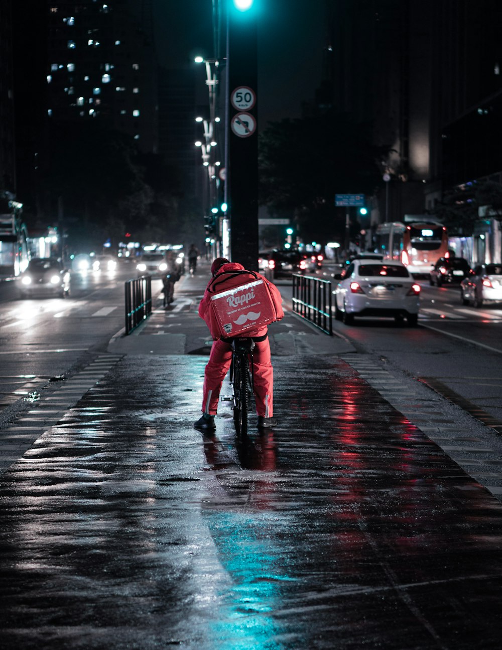 빨간 재킷과 파란 데님 청바지를 입은 사람이 밤 시간에 거리를 걷고 있다
