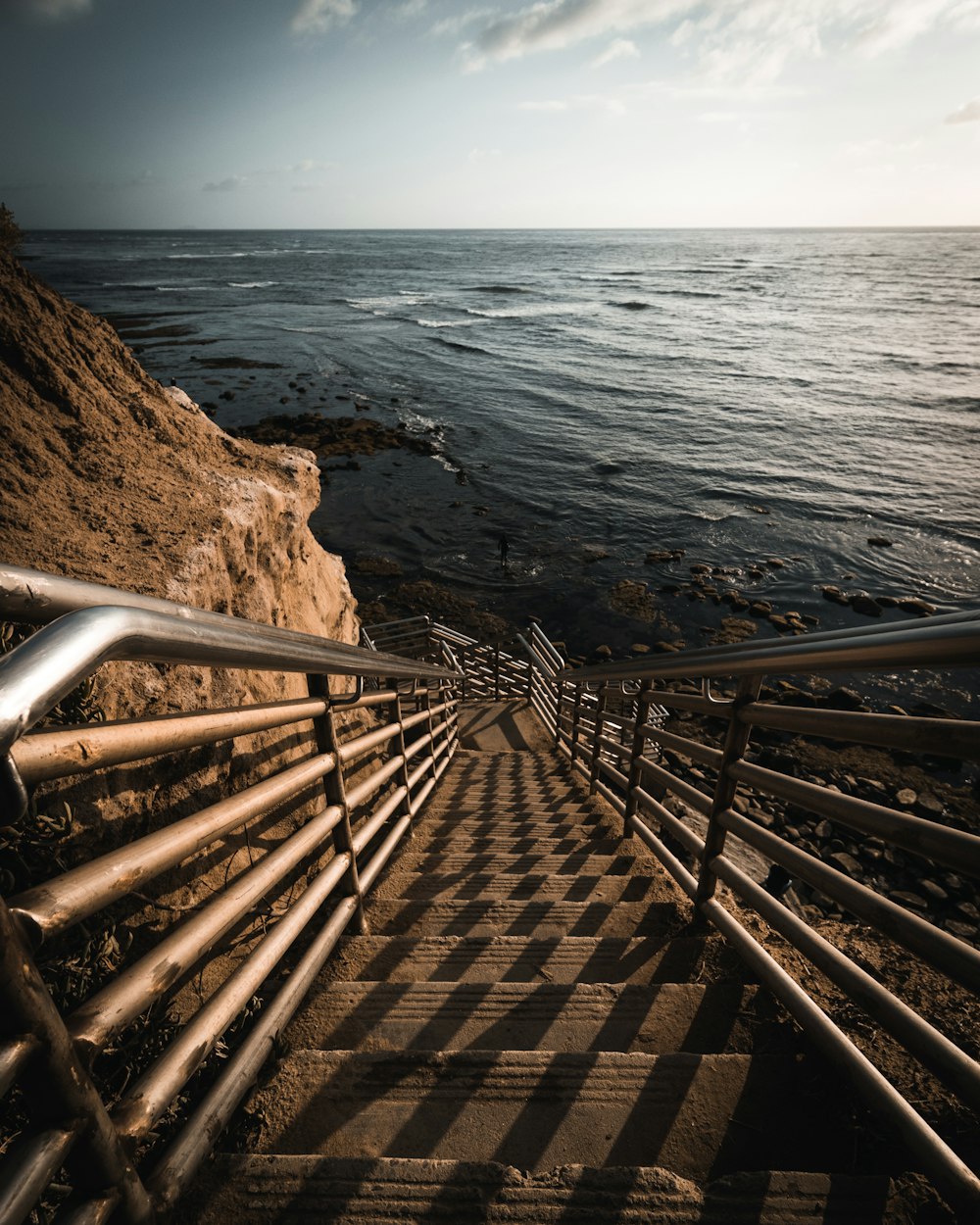 Escaleras de madera marrón en la playa rocosa marrón