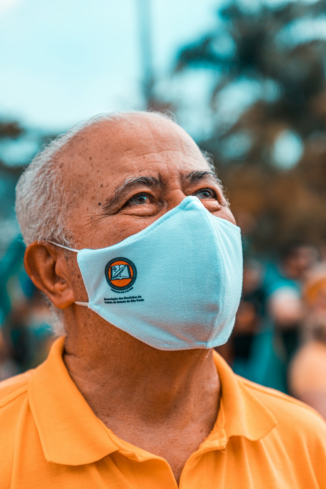 man in orange polo shirt wearing white face mask