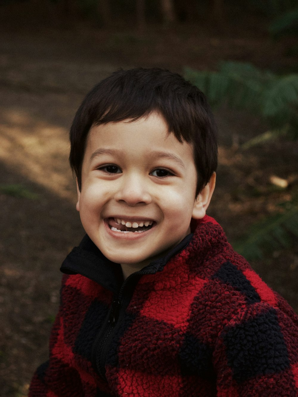 boy in red and black sweater smiling