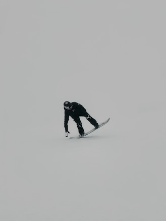 man in black jacket and pants standing on snow covered ground