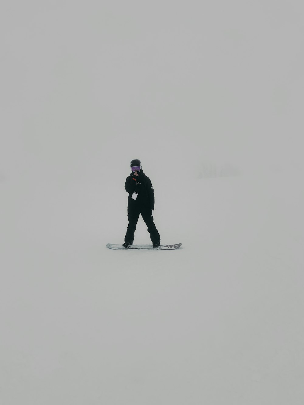man in black jacket and pants standing on snow covered ground