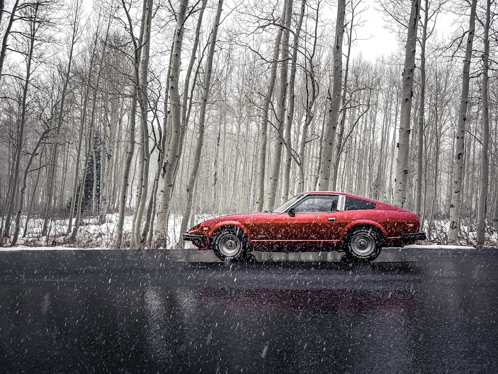 red coupe on road covered with snow